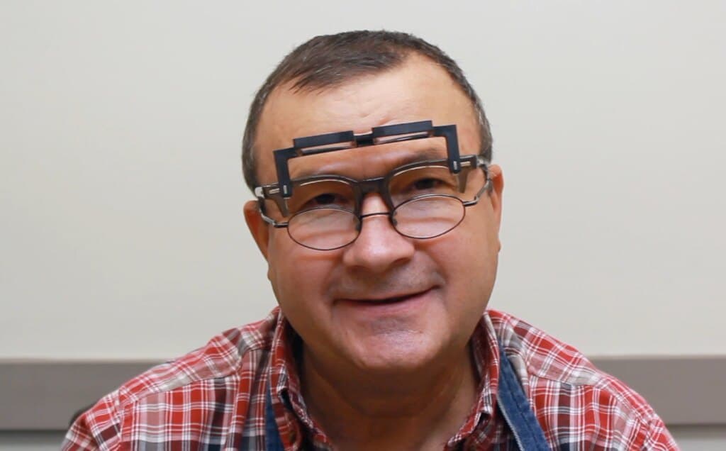 George Necula at his bench wearing a jeweler’s loupe