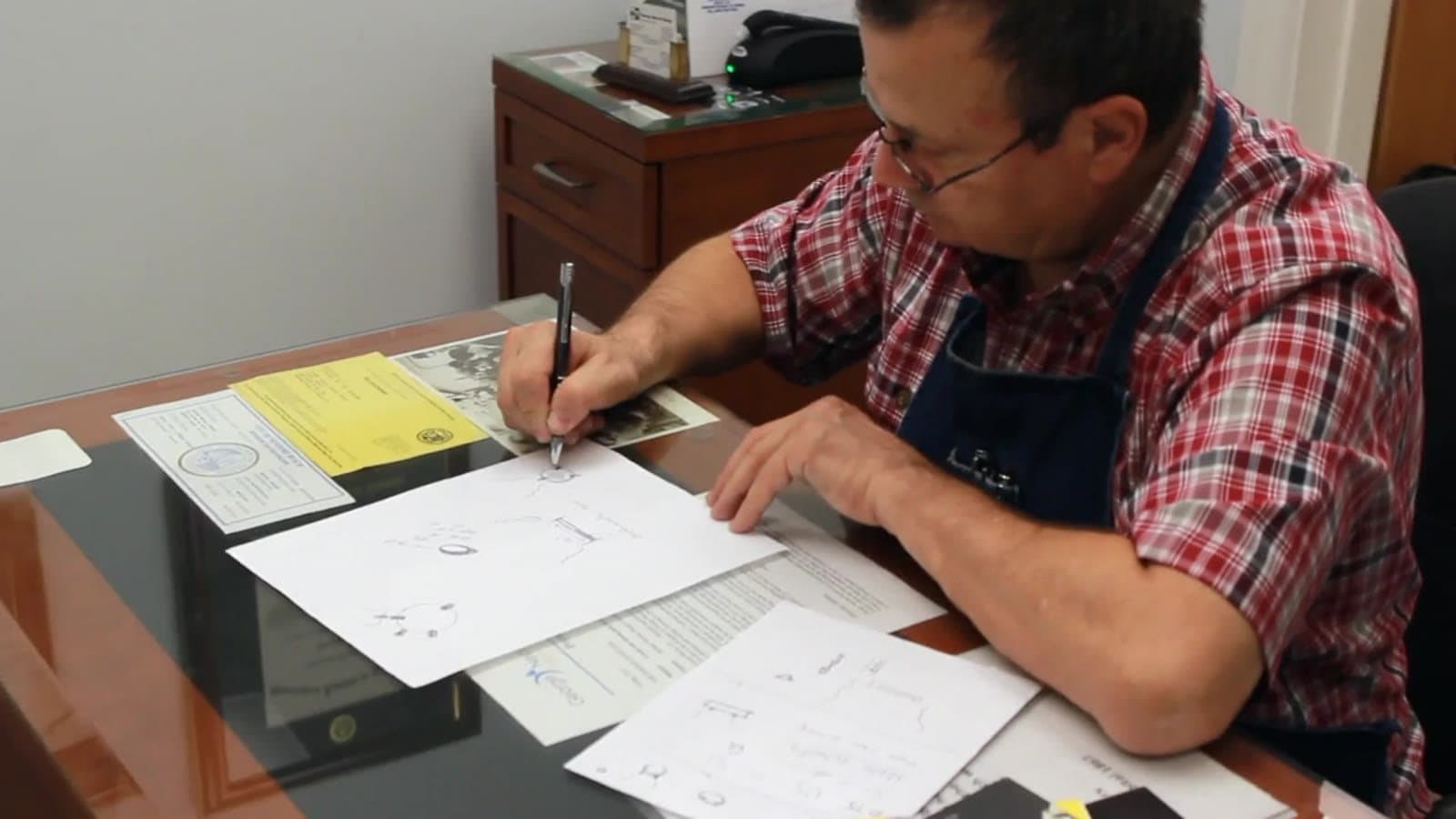 George Necula sketching a jewelry design at his workshop desk
