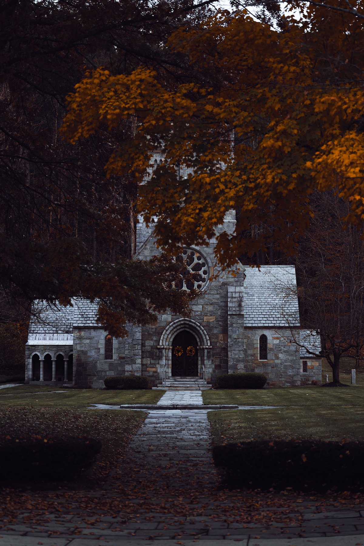 Gothic stone chapel framed by autumn maple leaves